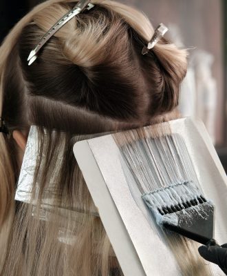 Young woman in a hairdressing salon dyes her hair blond